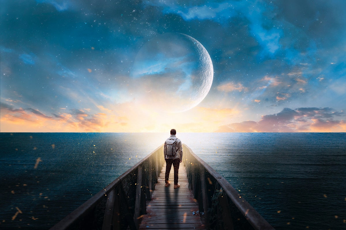 Ein Mann steht mit dem Rücken auf einem Steg ins Wasser vor dem Mond. Fantasielandschaft.