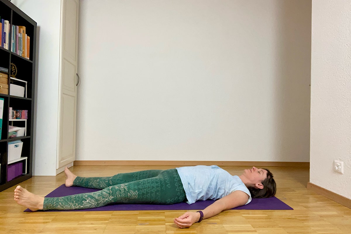 Katharina Balande in der Yoga Stellung Shavasana. Rückenlage. Arme und Beine gestreckt, leicht geöffnet.