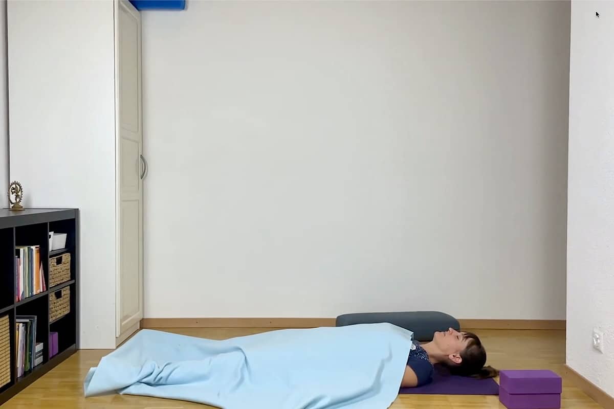 Frau liegt zugedeckt auf dem Rücken.