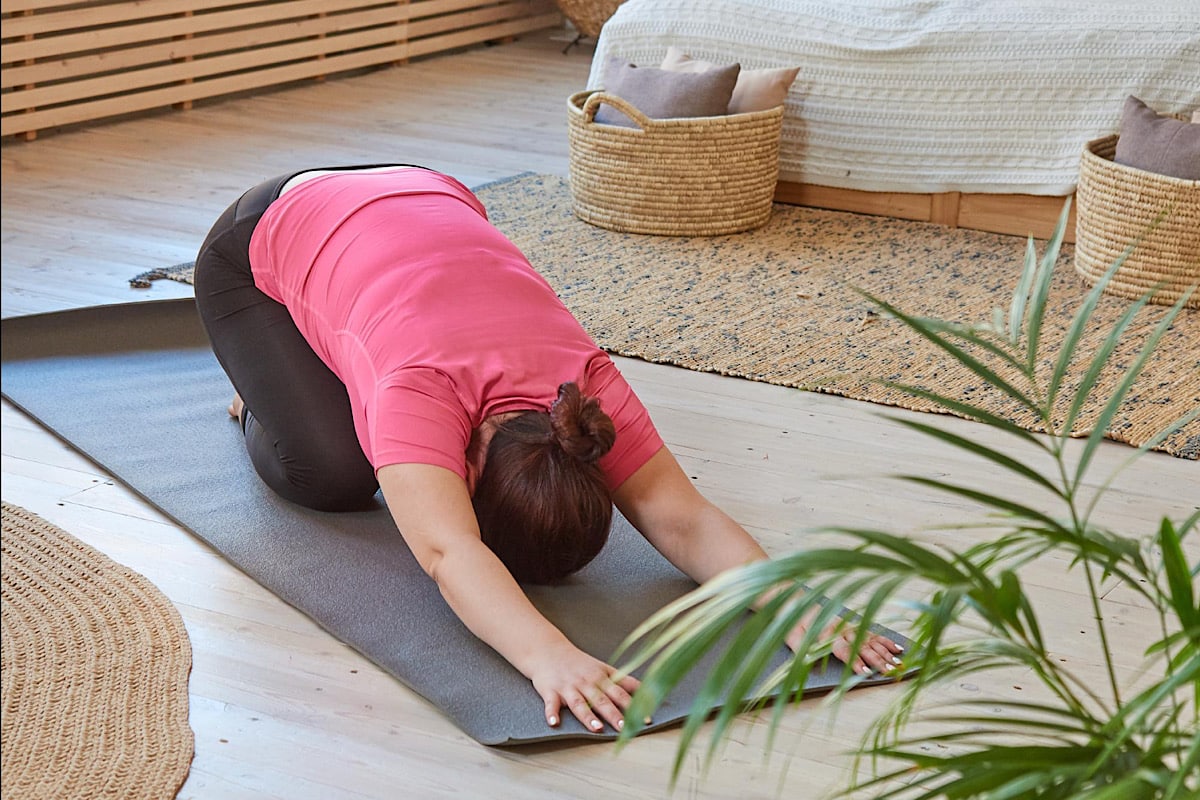 Frau macht Child's Pose zuhause.